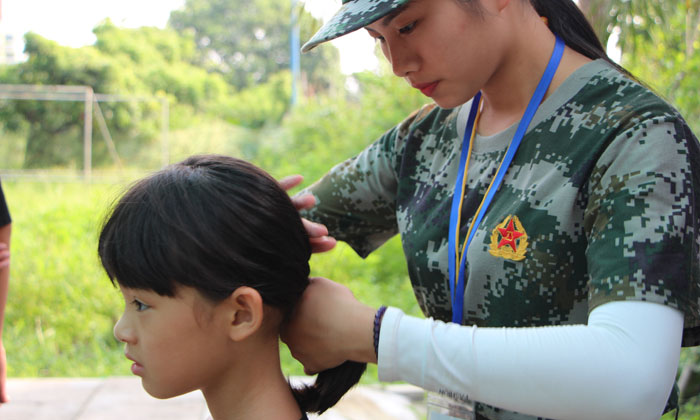 女教官細(xì)心的為孩子扎頭發(fā)